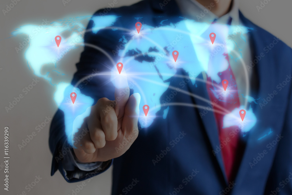 Businessman touching blue virtual world map on screen with connecting light trails from different locations Businessman touching blue virtual world map on screen with connecting light trails from different locations