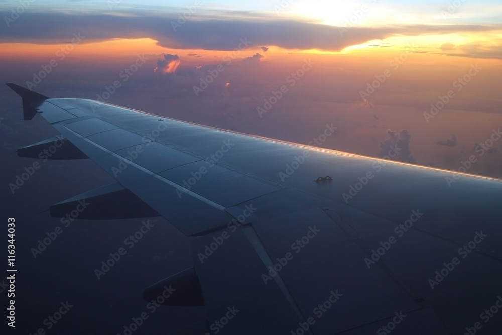 Rays of light in twilight sunset purple orange sky view from window airplane, fly over the ocean at evening time Rays of light in twilight sunset purple orange sky view from window airplane, fly over the ocean at evening time