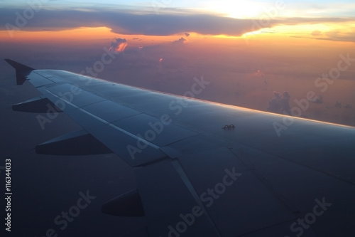 Rays of light in twilight sunset purple orange sky view from window airplane, fly over the ocean at evening time