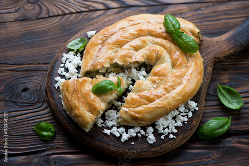Burek stuffed with cheese and spinach in a rustic wooden setting
