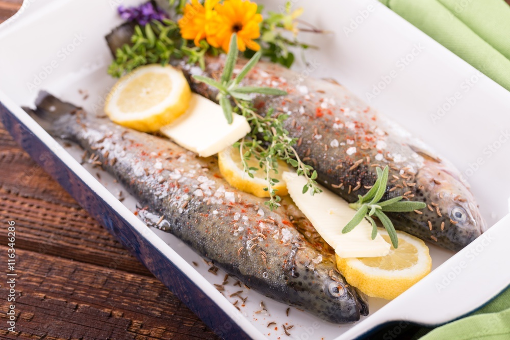 Trouts in blue ceramic pan with butter and lemon Trouts in blue ceramic pan with butter and lemon