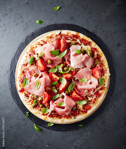 Pizza topped with black forest ham, capers and tomatoes

