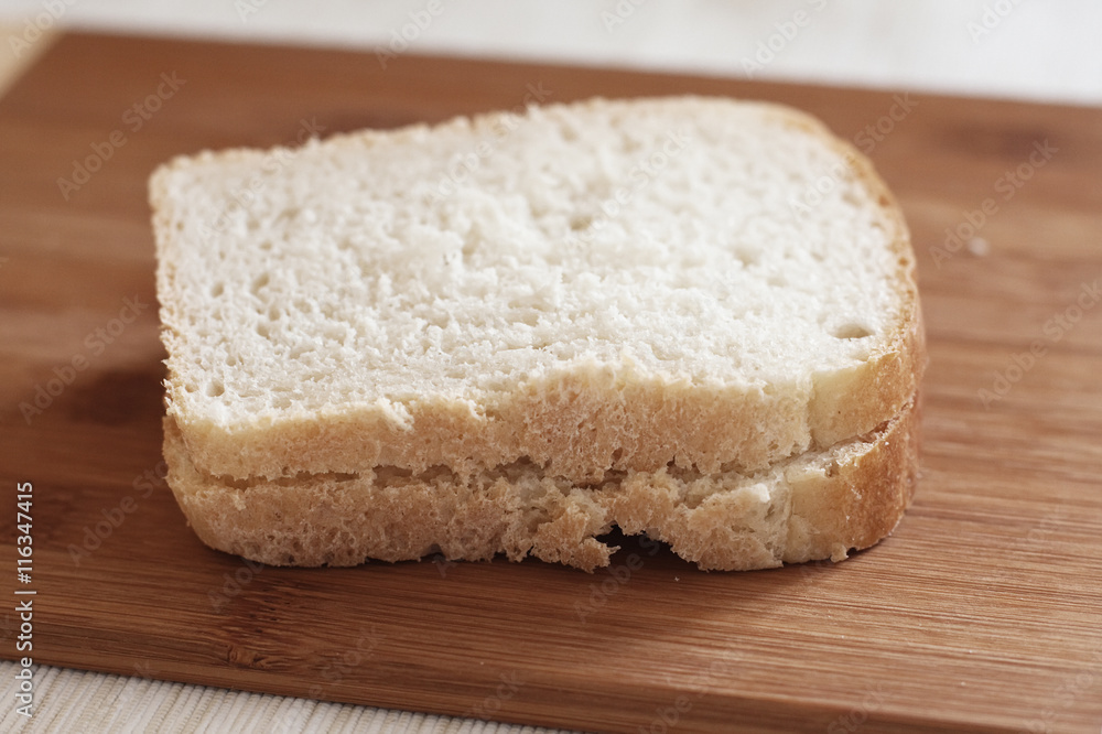 Two pieces of white bread on wooden cutting board Two pieces of white bread on wooden cutting board