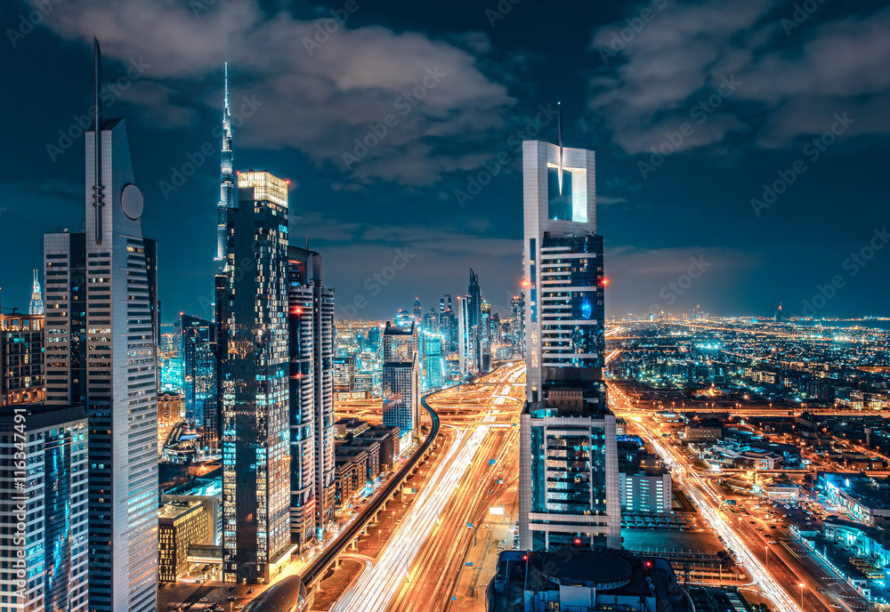 Fototapeta premium Scenic Dubai downtown architecture. Nighttime skyline with illuminated skyscrapers and highway. Fantastic travel background.