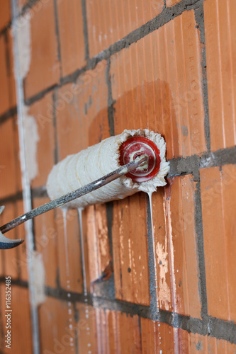 primer on the brick wall with a roller