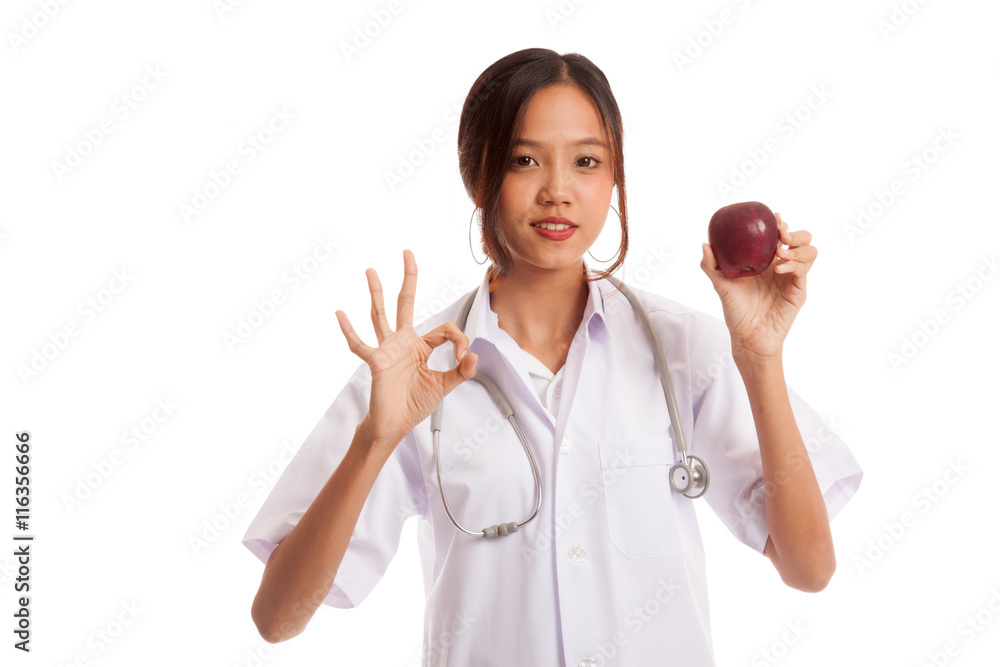 Young Asian female doctor show OK with apple isolated on white background Young Asian female doctor show OK with apple isolated on white background