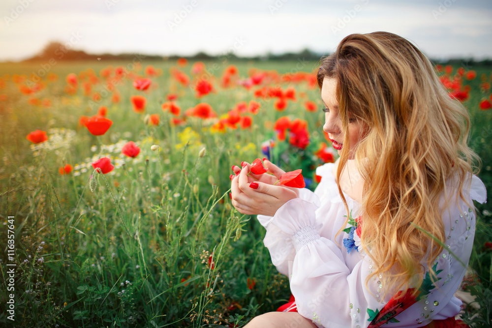 young beautiful woman with blond long hair in national dress red skirt and a white shirt with a wreath of flowers in a field of poppies and wheat young beautiful woman with blond long hair in national dress red skirt and a white shirt with a wreath of flowers in a field of poppies and wheat