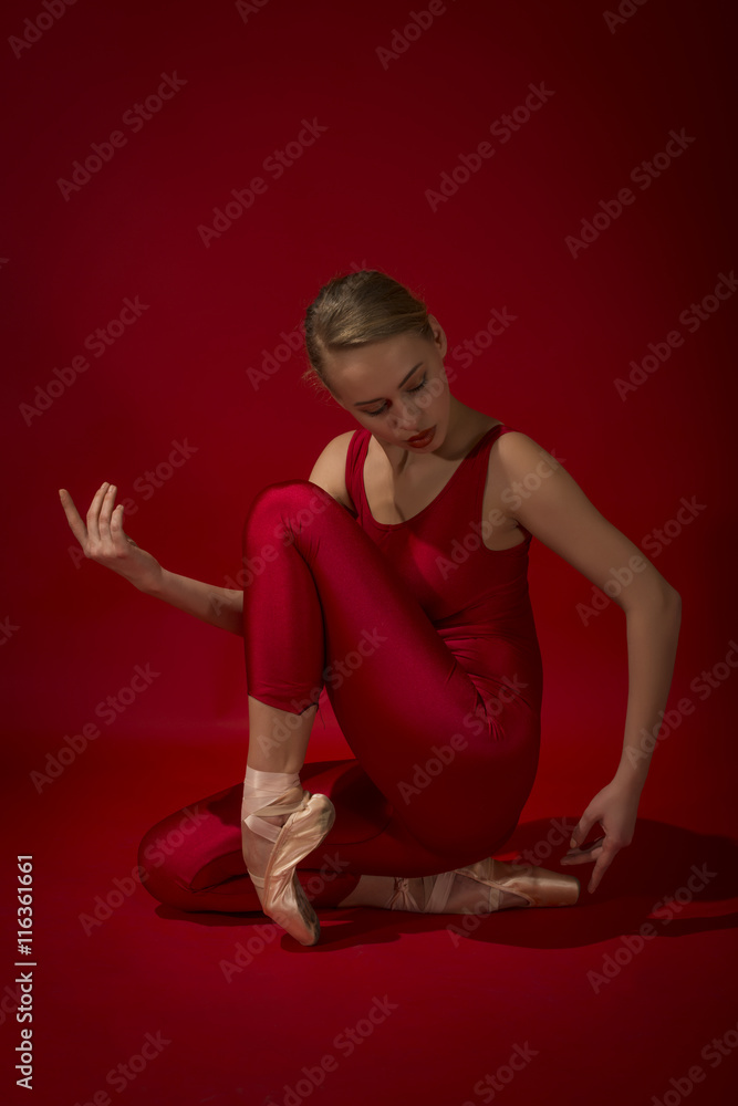 Ballerina in red outfit posing on toes, studio shot on red background. Young beautiful dancer posing in studio Ballerina in red outfit posing on toes, studio shot on red background. Young beautiful dancer posing in studio