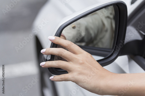 the girl in the car with beautiful manicure adjusts the rear view mirror