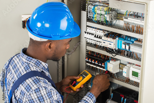 Technician Examining Fusebox With Multimeter Probe