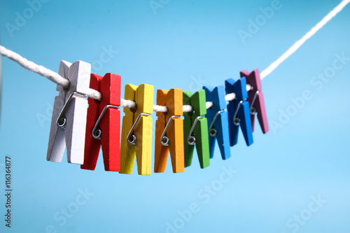 String of colorful clothes pegs on line against blue background