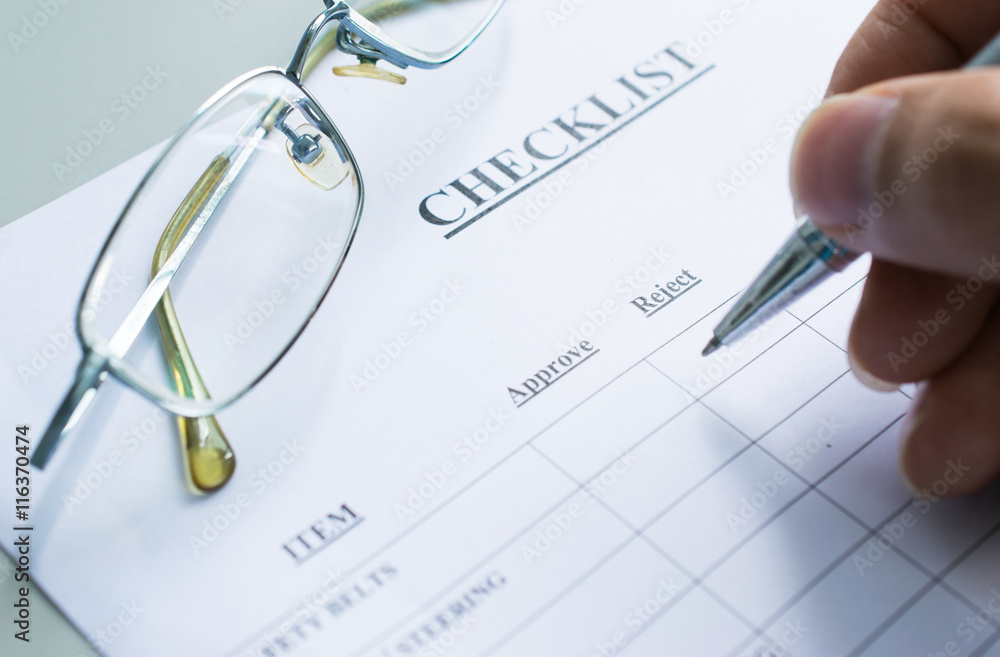 Hand with pen and glasses over checklist form Hand with pen and glasses over checklist form