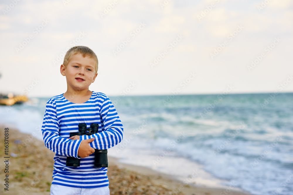 The little boy in the vest with the binoculars , walks on the beach The little boy in the vest with the binoculars , walks on the beach