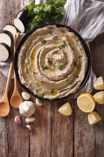 Middle Eastern cuisine: baba ghanoush closeup in a plate. vertical top view
