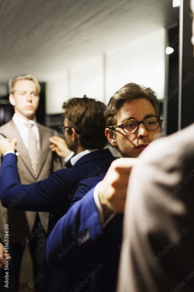 Salesman adjusting customer's suit in fitting room at clothing store Salesman adjusting customer's suit in fitting room at clothing store