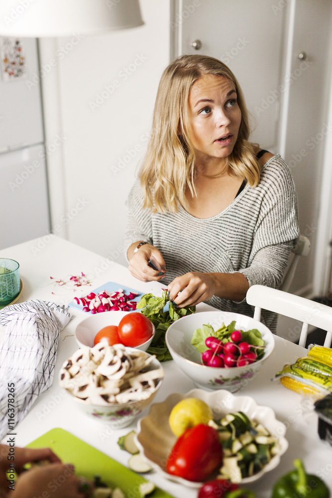 Young woman looking away while cutting vegetables in kitchen Young woman looking away while cutting vegetables in kitchen
