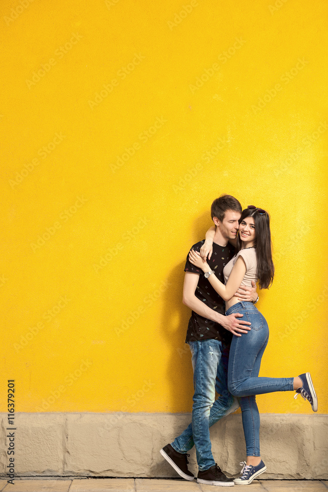 Smiling happy couple on yellow wall