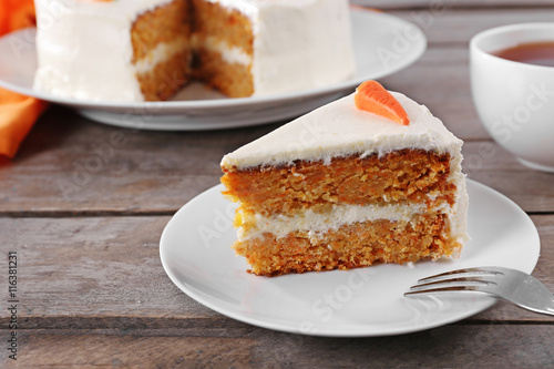 Delicious carrot cake with tea on wooden table