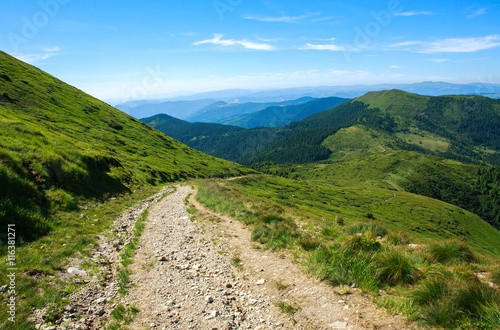 Fototapeta Naklejka Na Ścianę i Meble -  Soil road in mountains on background blue sky in summer