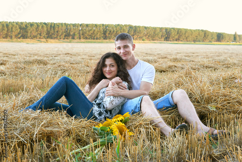 happy young couple sit in wheaten field at evening, romantic people concept, beautiful landscape, summer season
