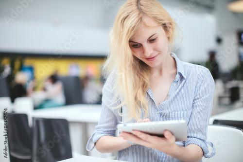 girl with a tablet in hands sitting in a shopping center, business center