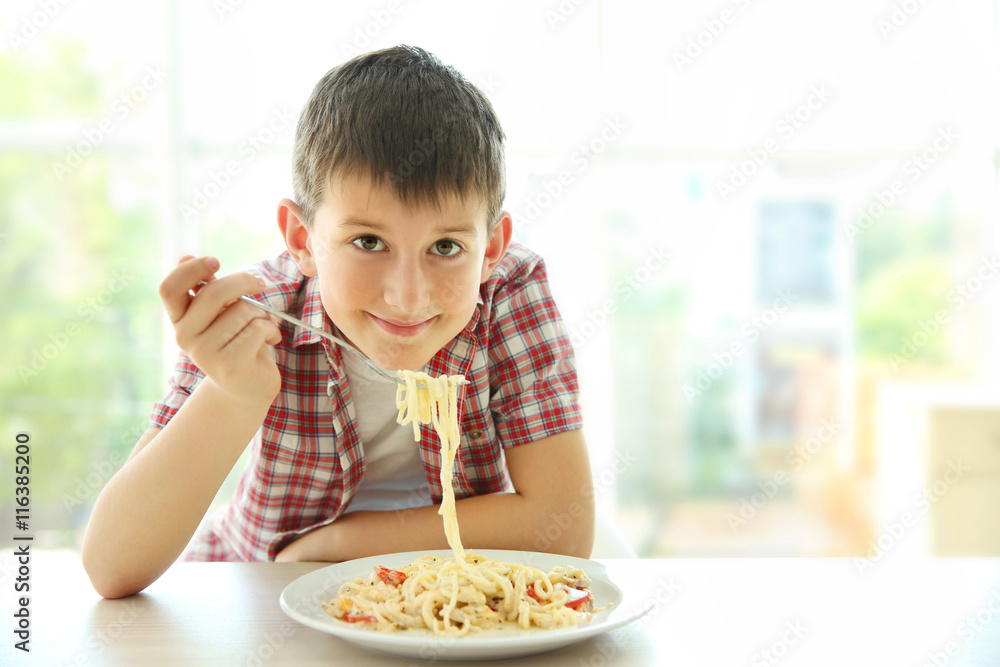 Cute boy eating spaghetti on kitchen Cute boy eating spaghetti on kitchen