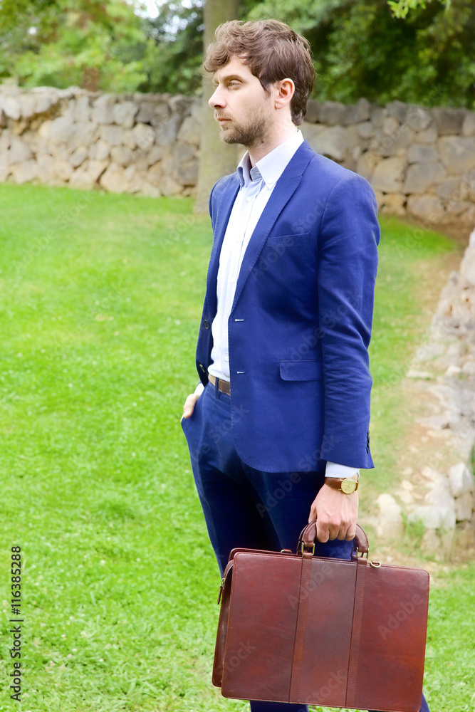 Handsome business man waiting for appointment in park wide shot Handsome business man waiting for appointment in park wide shot