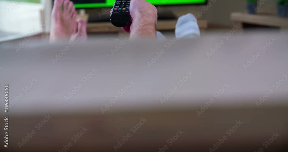 A couple is watching TV and their feet are on the table. They're changing the channels and just relaxing. Close-up shot.
A couple is watching TV and their feet are on the table. They're changing the channels and just relaxing. Close-up shot.