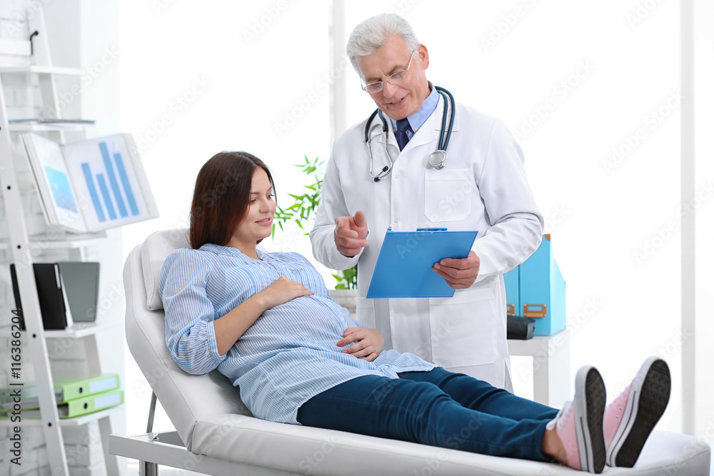 Fototapeta premium Young pregnant woman visiting doctor