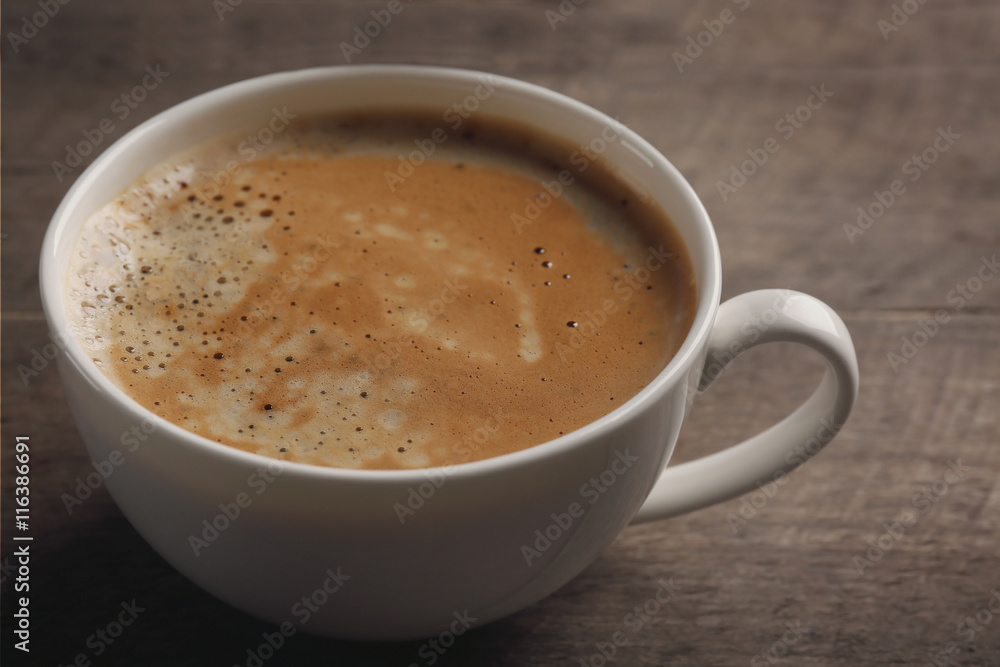 White cup of coffee on wooden background