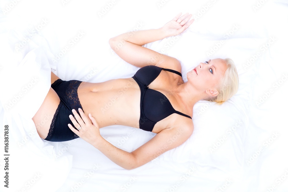 A young blonde woman laying in bed.