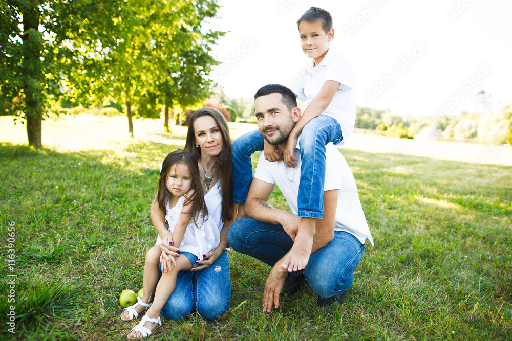 Parents Sitting With Children In Field Of Summer Flowers.Happy family having weekend in summer park Parents Sitting With Children In Field Of Summer Flowers.Happy family having weekend in summer park