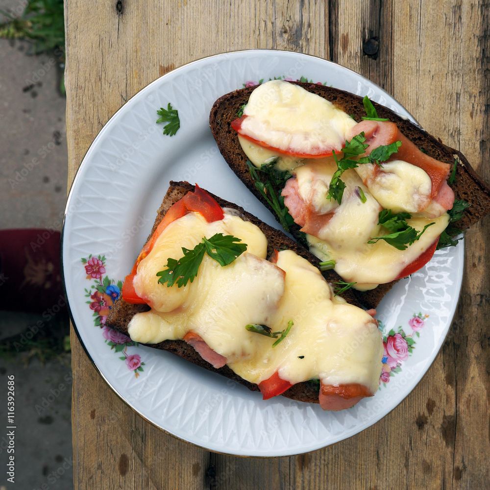 Hot sandwiches with cheese, tomatoes and sausages