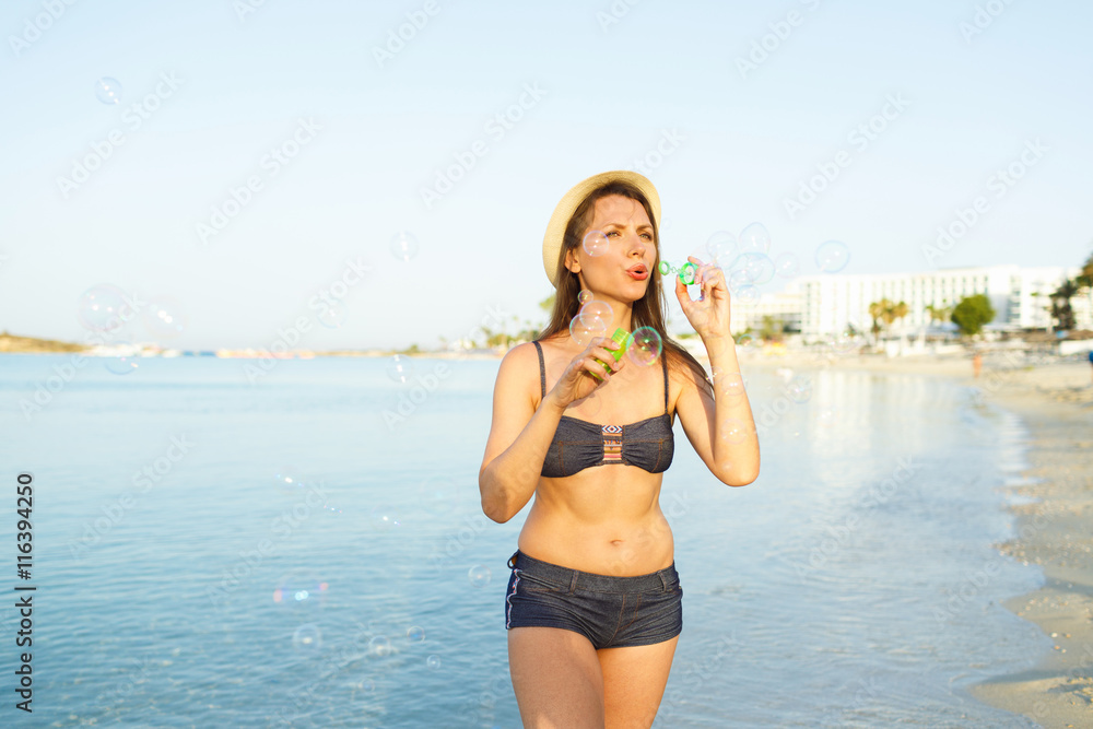 Youngwoman blowing soap bubbles on the seashore