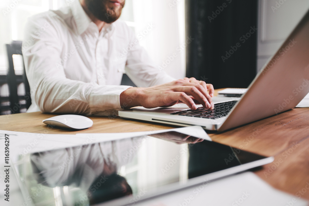 Man working at the office next to a window wearing white shirt Man working at the office next to a window wearing white shirt