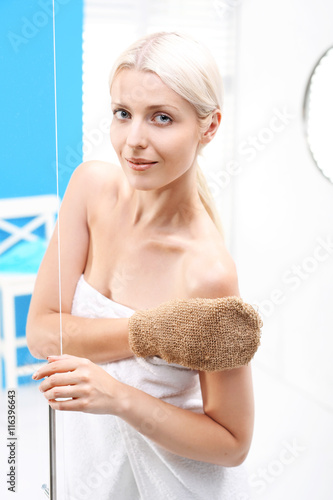 Prysznic. Kobieta masuje ciało rękawicą do masażu pod prysznicem