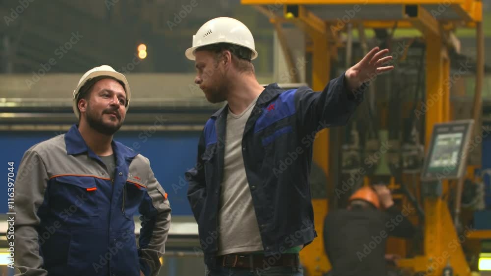 two engineers smile, laugh and shake hands in heavy industry factory two engineers smile, laugh and shake hands in heavy industry factory