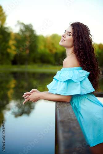 Summer girl portrait. Young woman smiling happy on summer or spring day outside in park by lake photo