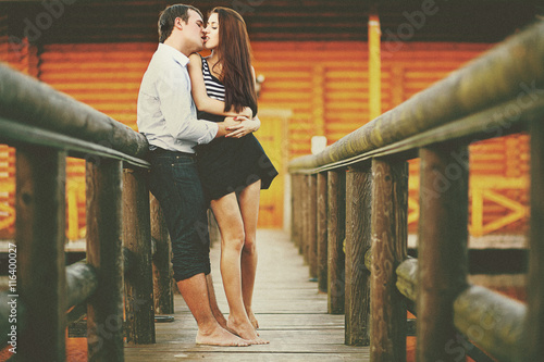 Barefooted love - couple kisses ardently on the wooden bridge photo