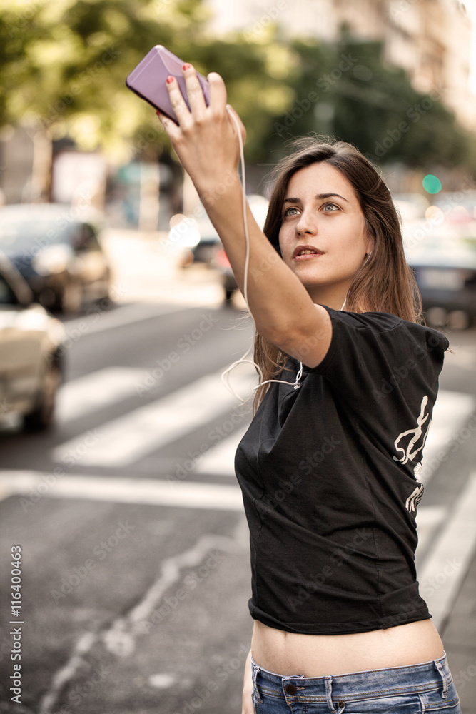 Fototapeta premium Young woman taking a photo with her phone