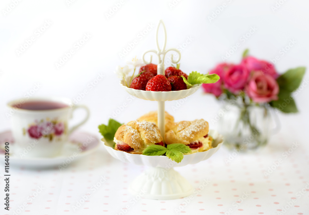 Cream puffs cakes or profiterole filled with whipped cream served with strawberries in plateau Cream puffs cakes or profiterole filled with whipped cream served with strawberries in plateau