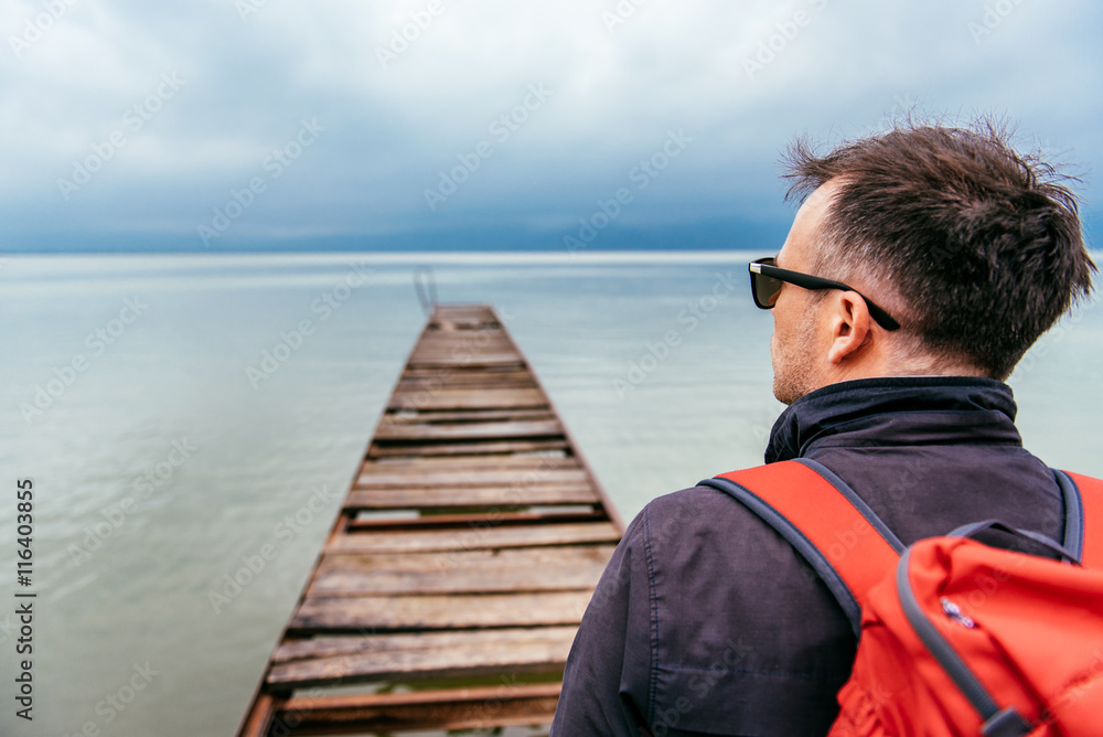 Fototapeta premium Man standing on a river dock and looking sideways