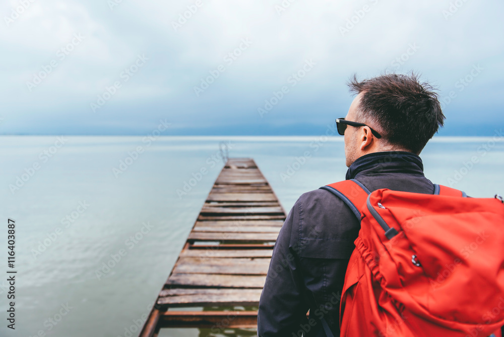 Fototapeta premium Man standing on a river dock and looking sideways