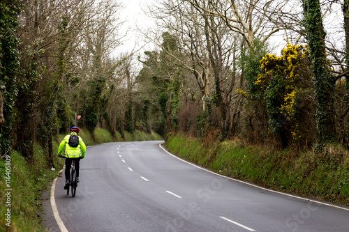 man riding a bicycle up a country road in high-visibility jacket  © jazzygeoff
