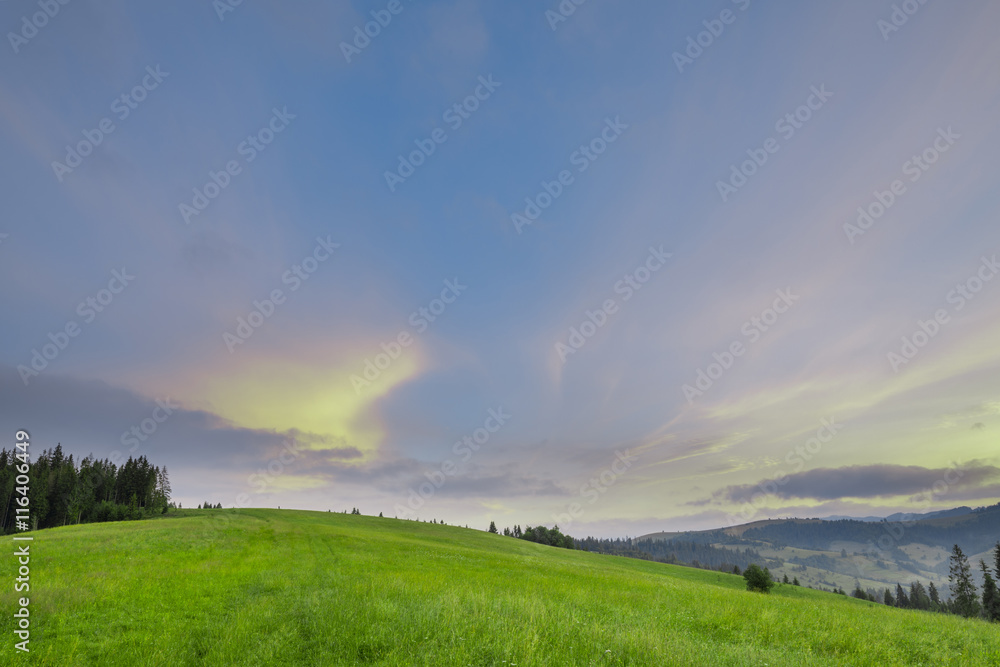 Mountain slope with green grass against the sky