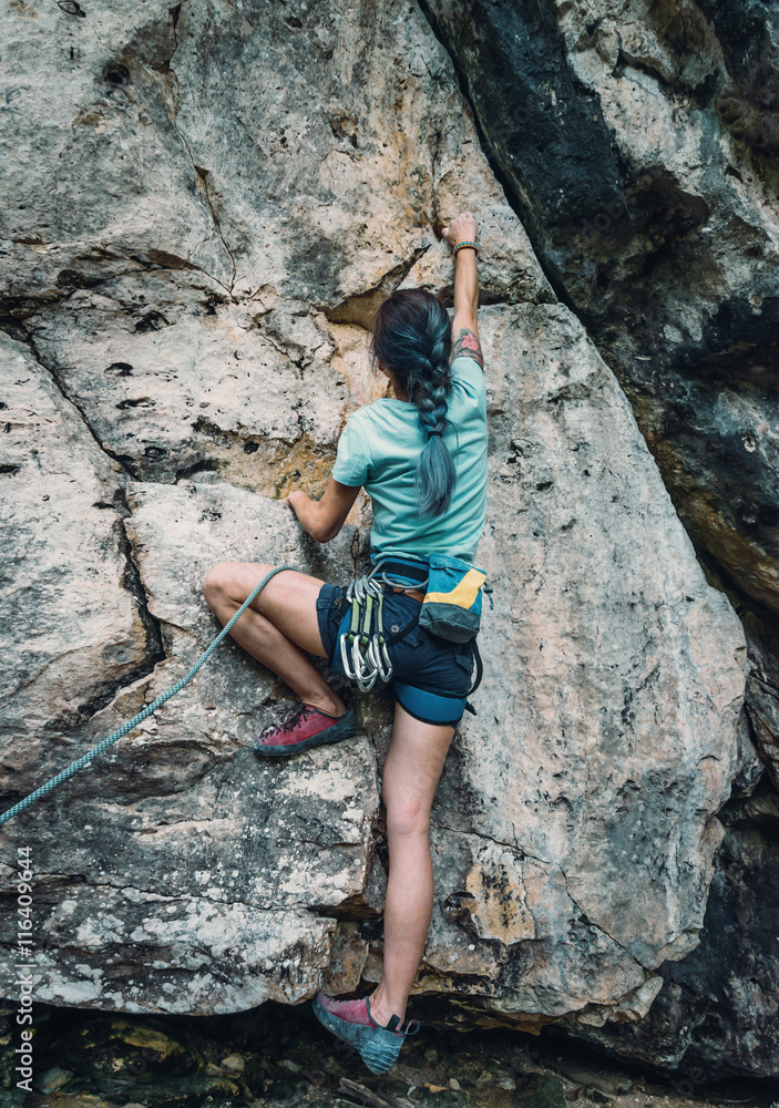 Sportswoman climbing the rock wall