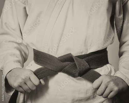Martial arts Master tightening black belt. Retro black and white toning