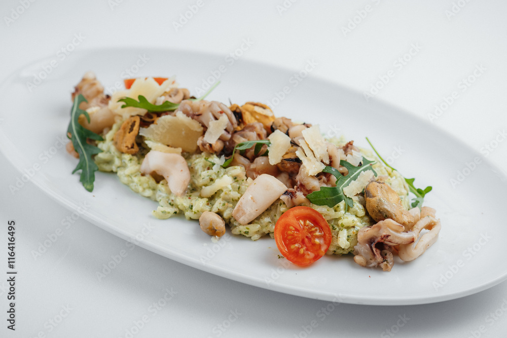risotto with seafood, tomatoes and arugula on a white plate risotto with seafood, tomatoes and arugula on a white plate