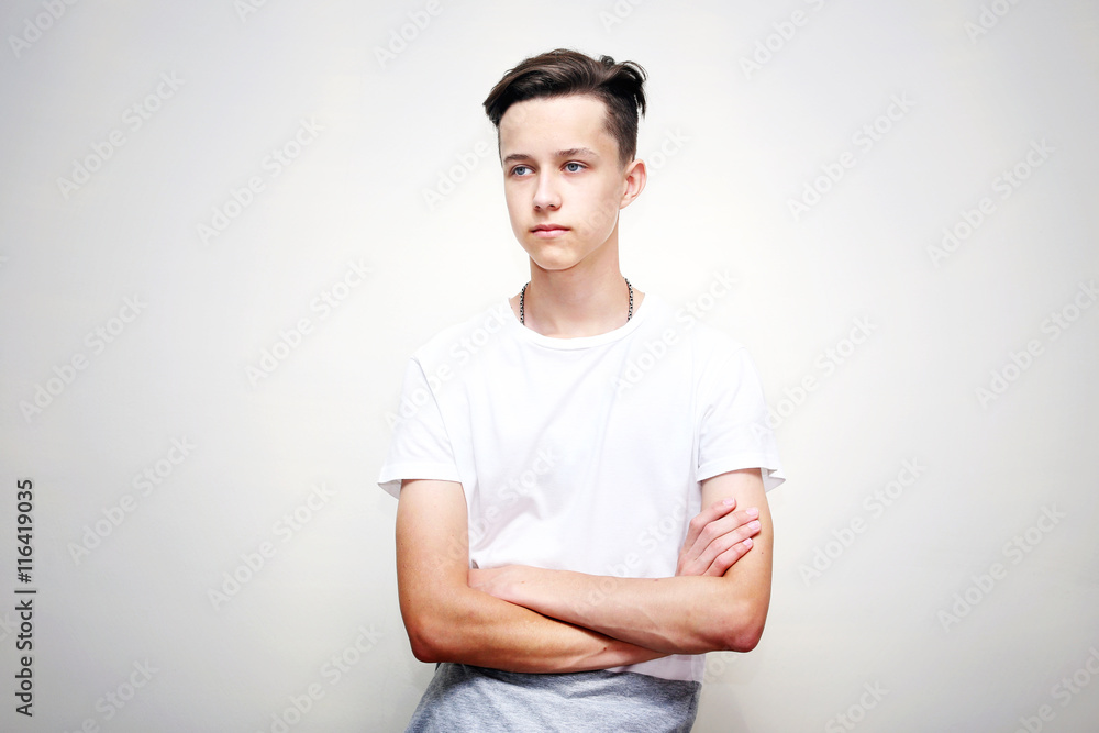 Portrait of a smart young man standing with arms crossed against gray background Portrait of a smart young man standing with arms crossed against gray background