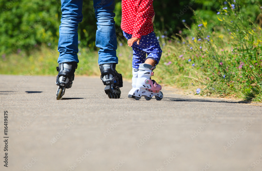 father teaching little daugther to roller skate in summer father teaching little daugther to roller skate in summer
